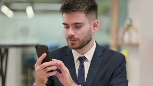 Businessman Celebrates After Good News on Smartphone