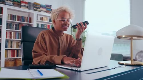 Smiling Person Using Laptop and Talking on Smartphone