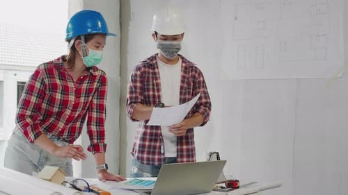 Construction workers with blueprint meeting and discussing at construction site