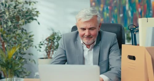 Gray Haired Man Smiling at Computer in Office