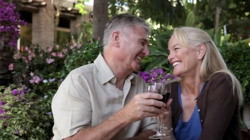 Mature Couple Laughing, Drinking Wine in Garden