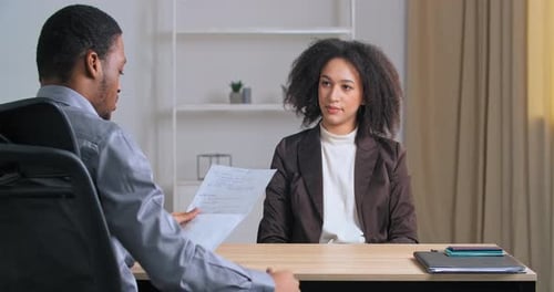 Curlyhaired Young Ethnic Woman Manager Businessperson Worker Sits in Office Talking Gives Document