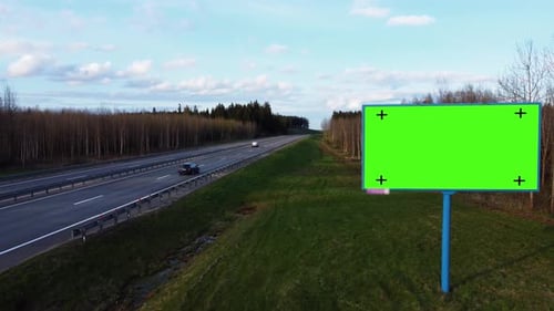 Billboard poster with green screen and tracking markers on a highway.