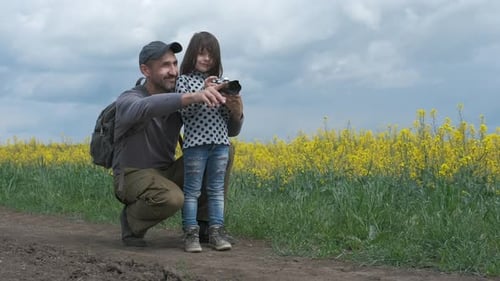 Father and Child Photographing Flowers in Rural Field