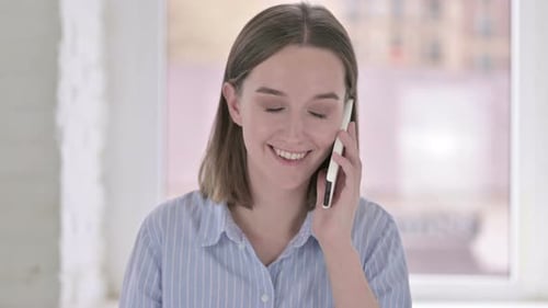 Porträt einer fröhlichen jungen Frau, die auf dem Smartphone spricht
