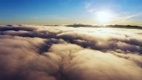 Sun Shining Brightly Above White Fluffy Clouds at Sunrise