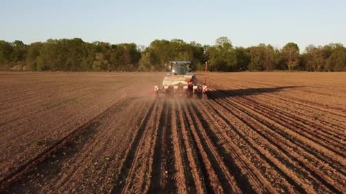 Tractor Working in Field at Sunset