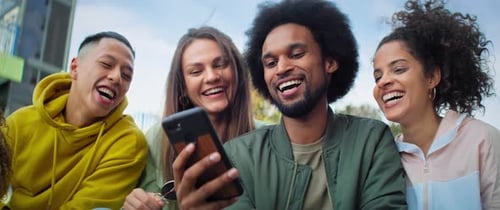 Friends Laughing While Looking at Mobile Phone Together