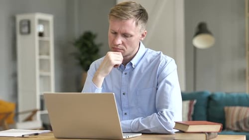 Man Typing on Laptop Computer at Table