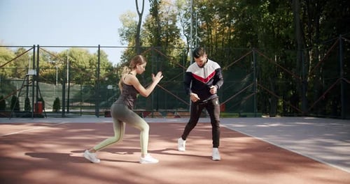 Woman and Man Doing Lunges on Outdoor Court