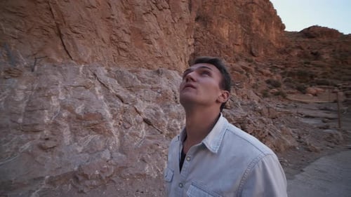 Orbit Shot Around Man Admiring Huge Rocky Massif Surrounding Narrow Gorge with Road