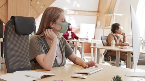 Femme d'affaires caucasienne portant un masque travaillant au bureau