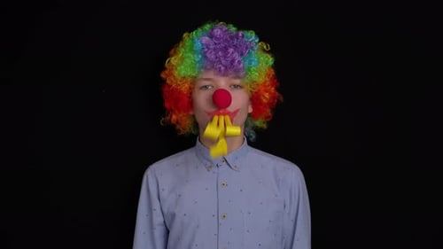 Clown Playing Noisemaker Against Black Background