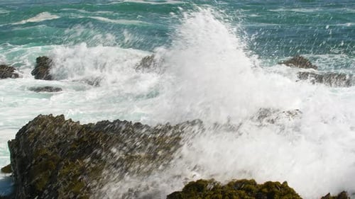 Olas del océano chocando contra las rocas con el mar azul de fondo (SLOWMO)