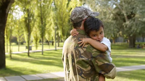 Soldier Holding Son in Sunny Urban Park