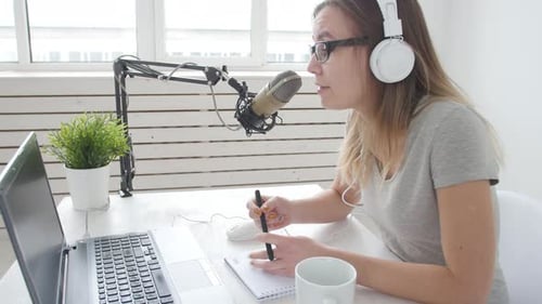 Concept of Streaming and Broadcasting. Young Cheerful Girl in the Studio Speaks Into a Microphone