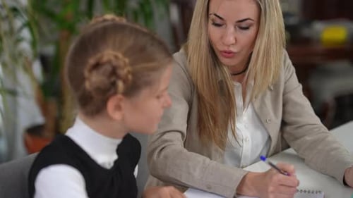 Portrait d'une belle femme intelligente parlant du matériel explicatif à une étudiante adolescente assise au bureau