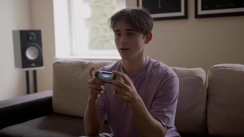 Teenager Playing Handheld Video Game on Couch