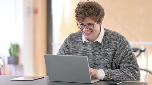 Man Celebrates Success While Working on Laptop