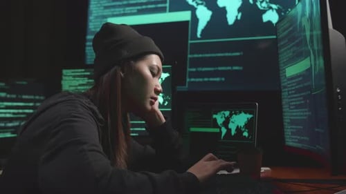 Une jeune femme asiatique qui s'ennuie utilise le piratage informatique et code sur plusieurs écrans d'ordinateur