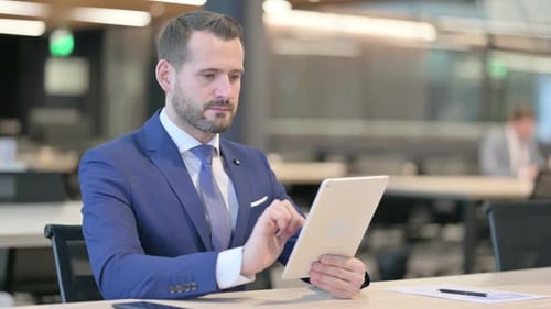 Middle Aged Businessman Using Tablet at Work
