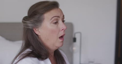 Woman Sneezing and Blowing Nose in Bedroom