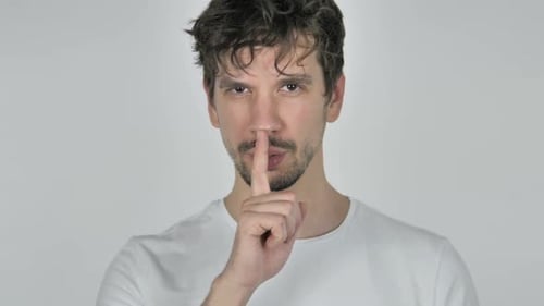 Portrait of Young Casual Man Gesturing Silence Finger on Lips