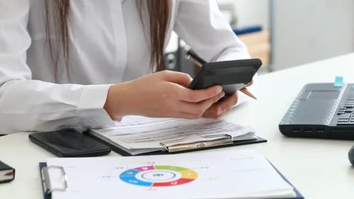 Woman Hands Counting on Calculator and Filling Documents in Modern Office