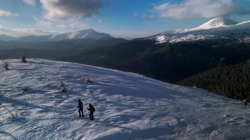 Drone Flying Over Couple of Hikers, Walking With Trekking Poles Towards the Summit in Winter