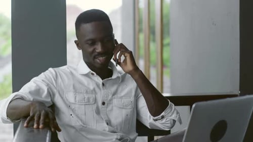 Man Talking on Phone While Using Laptop