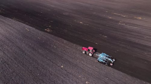 Tractor Plows Ground on Cultivated Farm Field