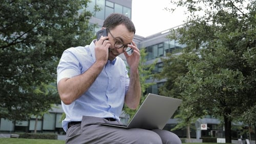 Businessman Working Outdoor in Park Using Laptop and Talking
