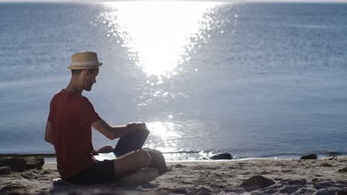 Man Working with Laptop on the Beach at Sunset