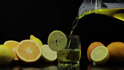 Yellow Liquid Poured into Glass with Citrus Fruit