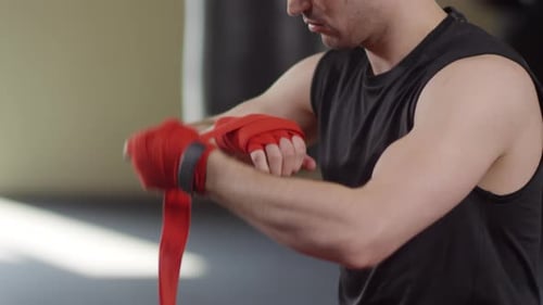 Boxer Wraps Hands with Red Wraps in Gym