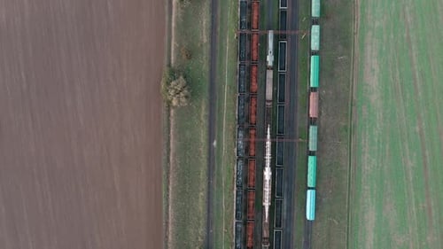 Eine Drohnenansicht von Eisenbahnwaggons am Bahnhof, umgeben von Feldern
