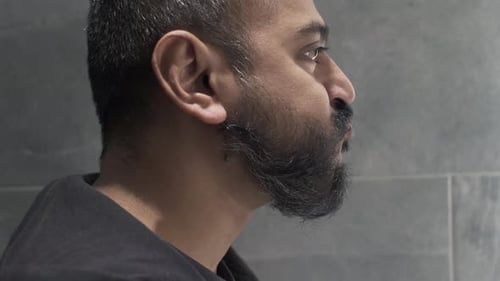 Ethnic Minority Adult Male Gargling Mouthwash In Bathroom. Side View, Locked Off