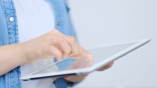 Close Up on the Hand of Young Handsome Woman Pointing and Touching the Screen of a Tablet with Her