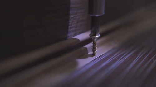Drill Fastening Screw into Dark Wood Surface