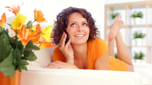 Woman is on the Telephone on White Sofa Indoor