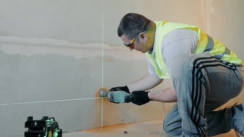 Un ouvrier du bâtiment perce un trou dans le mur sous la douille