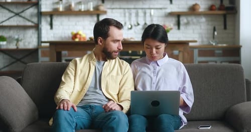 Man and Woman Looking at Laptop on Couch