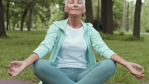 Portrait of Old Female Yogi Meditating in Park