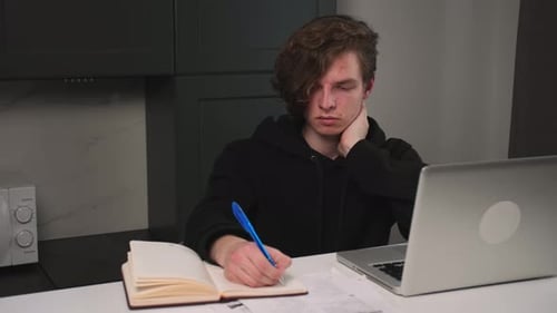 Serious Young Man Has Conference Video Calling By Webcam Writes Information to a Notebook Focused