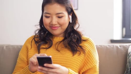 Woman Using Smartphone on Sofa Indoors