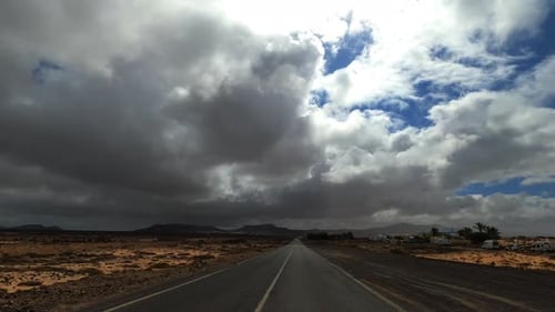 Dramatic sky landscape with long straight road and fast moving movement from car or van vehicle.
