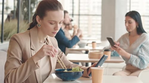 Young Woman with Smartphone Having Lunch at Food Court