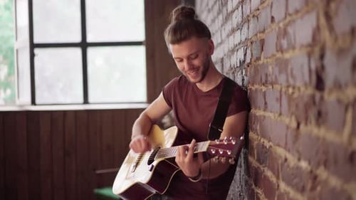 Man Playing Guitar, Leaning Against Brick Wall