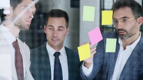 Geschäftsleute brainstorming mit Post-its auf Glasscheibe