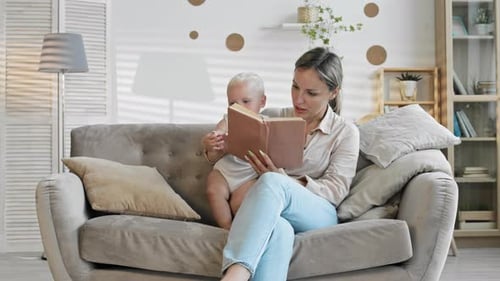Young Adult Reads to Infant on Couch